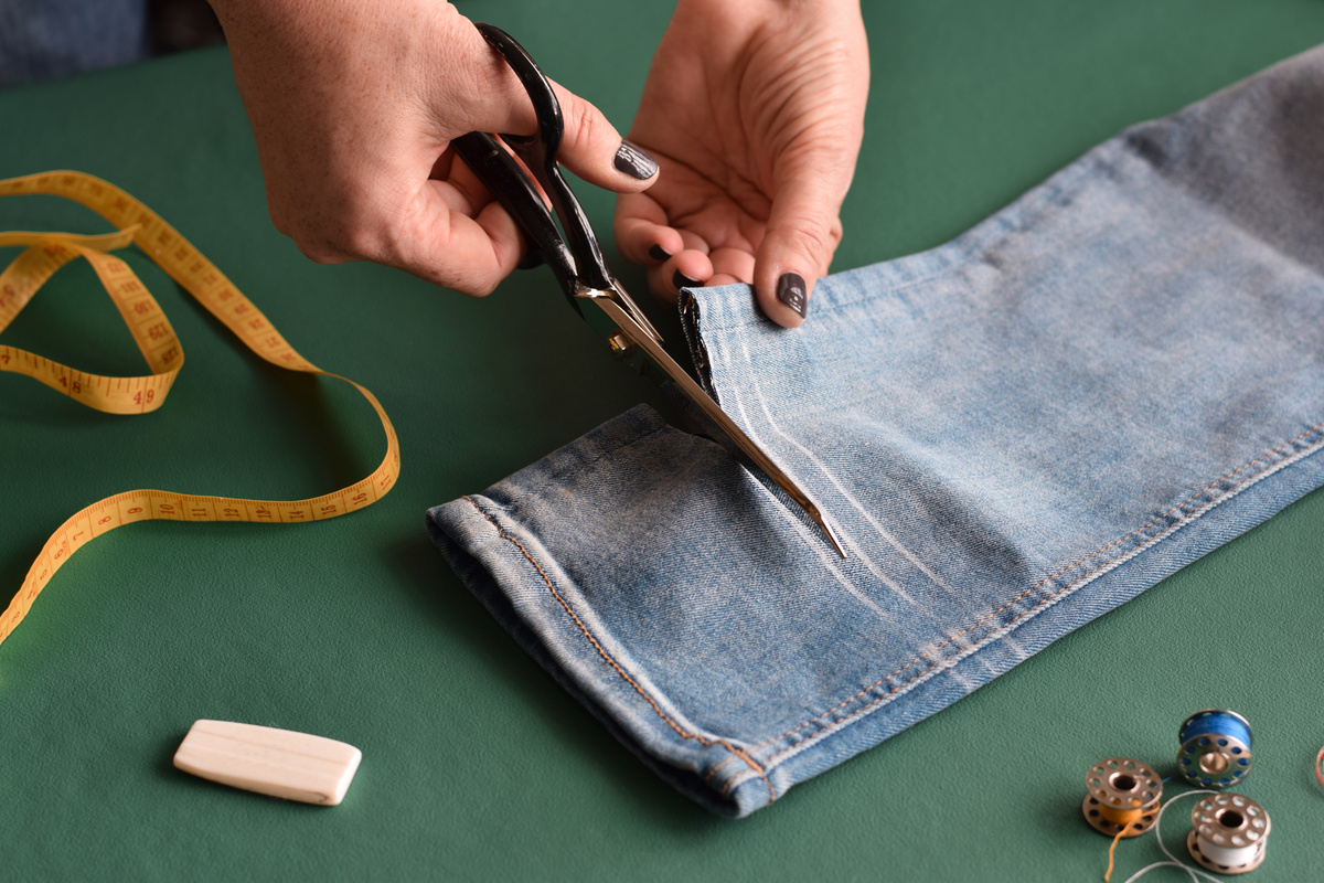 Seamstress Cutting Jeans with Scissors for Hemming